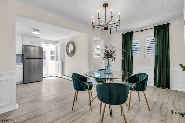 dining space featuring light wood-style flooring, a decorative wall, and a wealth of natural light