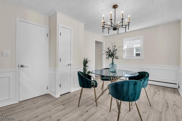 dining room featuring a wainscoted wall, an inviting chandelier, baseboard heating, light wood-type flooring, and a decorative wall