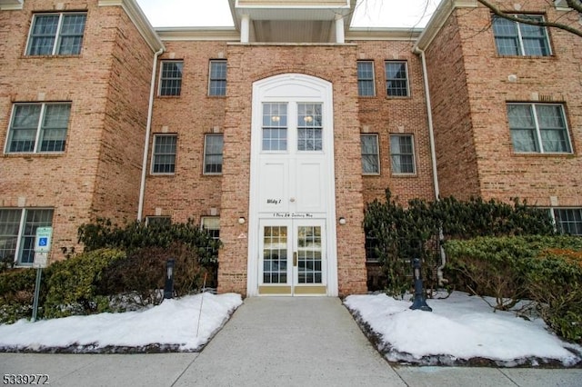 snow covered property entrance with brick siding