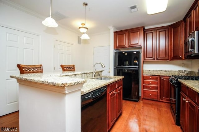 kitchen with pendant lighting, visible vents, a kitchen island with sink, a sink, and black appliances