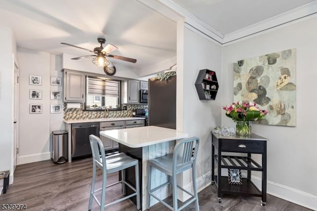 kitchen featuring a breakfast bar, dark wood-style flooring, tasteful backsplash, light countertops, and appliances with stainless steel finishes