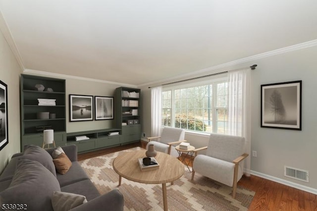 living area featuring baseboards, visible vents, wood finished floors, and ornamental molding