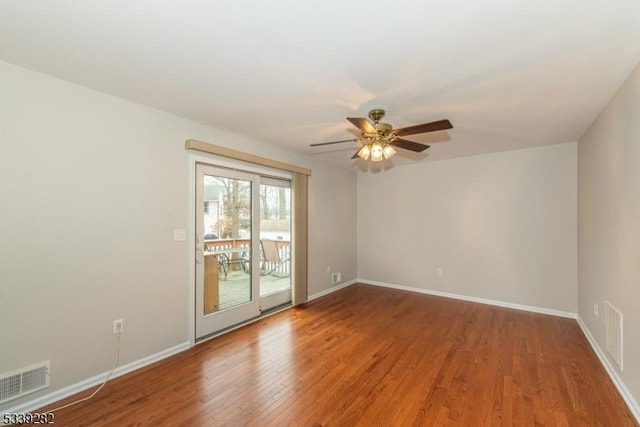 empty room featuring visible vents, ceiling fan, baseboards, and wood finished floors