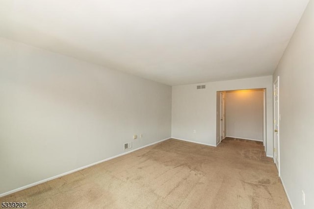 unfurnished room with baseboards, visible vents, and light colored carpet