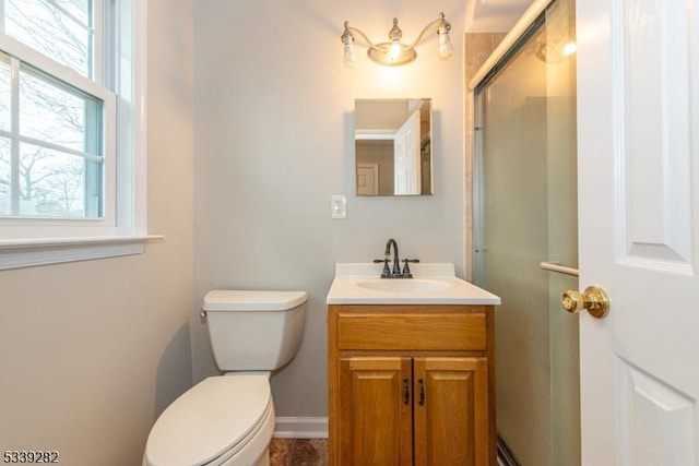 bathroom featuring toilet, vanity, baseboards, and a shower with shower door