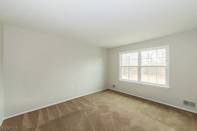 spare room featuring baseboards, visible vents, and light colored carpet