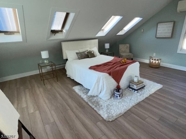 bedroom featuring a wall mounted air conditioner, lofted ceiling with skylight, a baseboard heating unit, wood finished floors, and baseboards