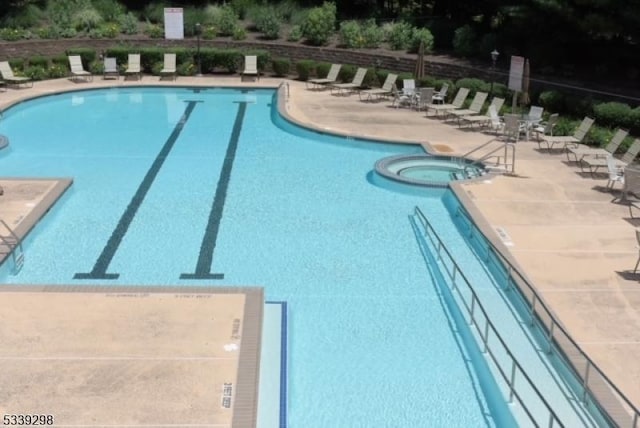 view of swimming pool with a pool with connected hot tub, a patio, and fence