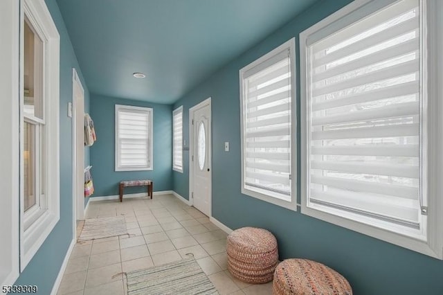 doorway to outside featuring baseboards and light tile patterned flooring