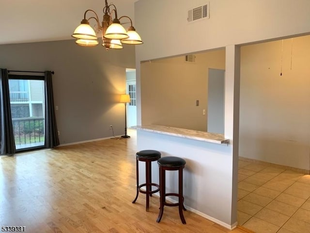 kitchen with an inviting chandelier, visible vents, a breakfast bar area, and decorative light fixtures