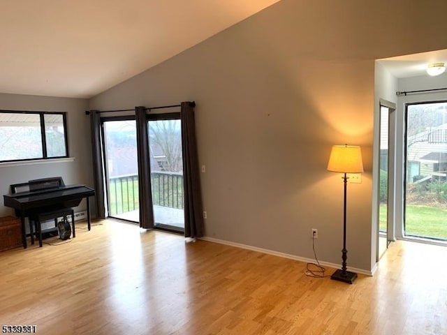 living room with light wood-style floors, a wealth of natural light, and vaulted ceiling