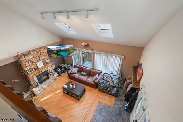 living area with a stone fireplace and lofted ceiling with skylight