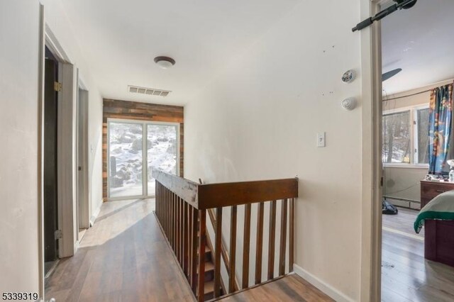 hall with wood finished floors, an upstairs landing, visible vents, baseboards, and baseboard heating