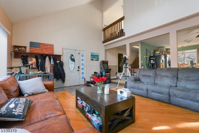 living room featuring high vaulted ceiling, stairs, and wood finished floors