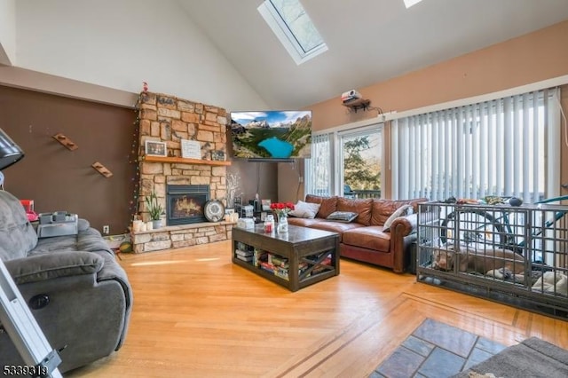 living room with a skylight, a fireplace, high vaulted ceiling, and wood finished floors