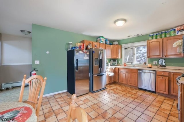 kitchen with brown cabinets, stainless steel appliances, a baseboard radiator, light countertops, and hanging light fixtures