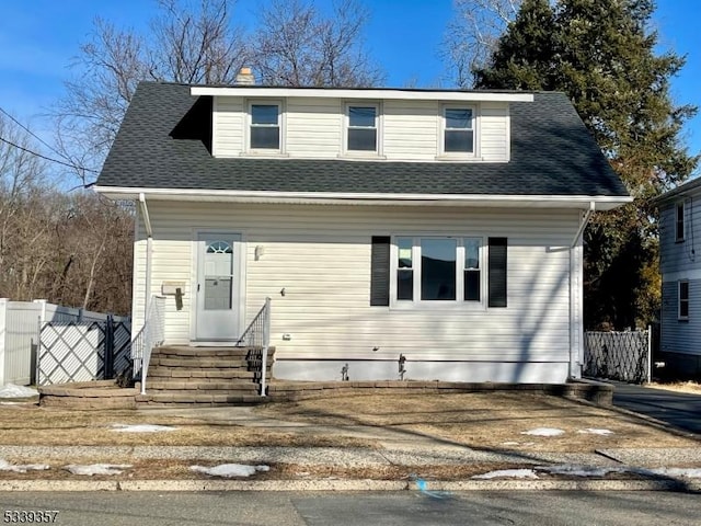 view of front of property with entry steps, roof with shingles, and fence