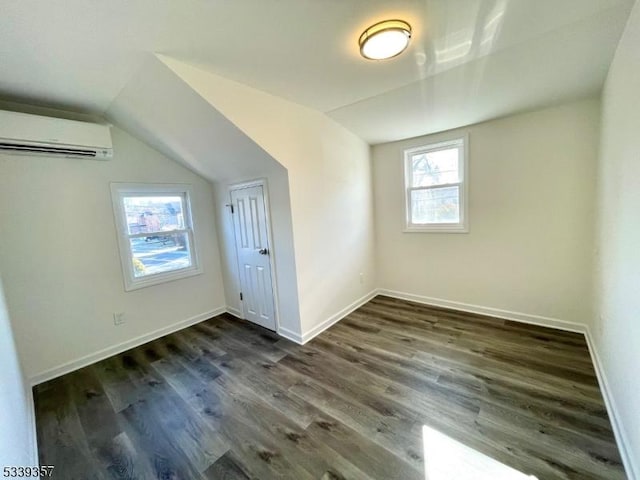 bonus room with dark wood finished floors, vaulted ceiling, and an AC wall unit