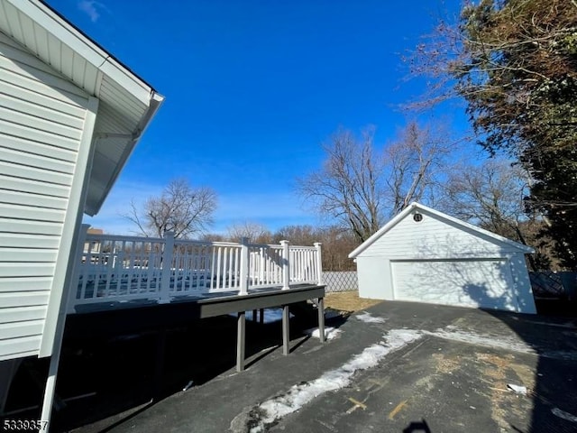 view of home's exterior featuring a garage, a wooden deck, and an outbuilding