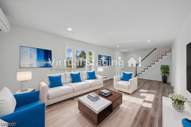 living area with a wall unit AC, recessed lighting, light wood-style floors, baseboards, and stairs