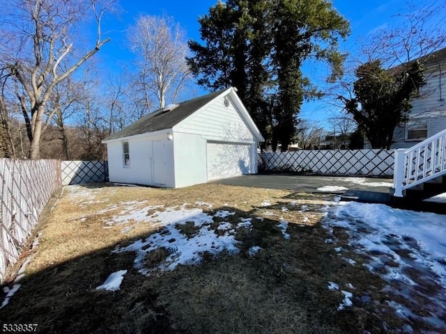 yard covered in snow with a garage, an outbuilding, and a fenced backyard