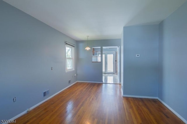 empty room featuring dark wood finished floors, visible vents, and baseboards