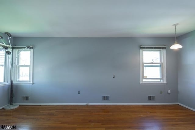 unfurnished room with baseboards, visible vents, and dark wood-style flooring