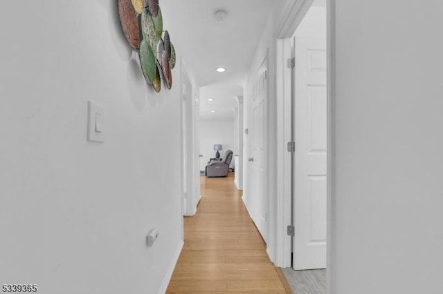 corridor featuring recessed lighting, light wood-type flooring, and baseboards