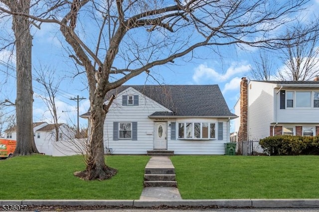 view of front facade featuring a shingled roof, a chimney, fence, and a front lawn