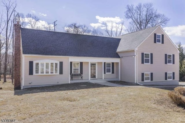 view of front facade with a patio area, a chimney, and a front lawn