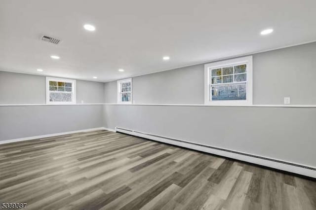 below grade area with visible vents, baseboard heating, wood finished floors, and recessed lighting