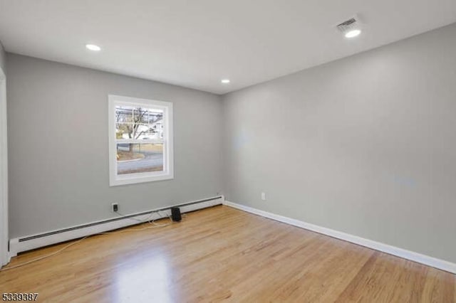 spare room with baseboards, a baseboard radiator, wood finished floors, and recessed lighting