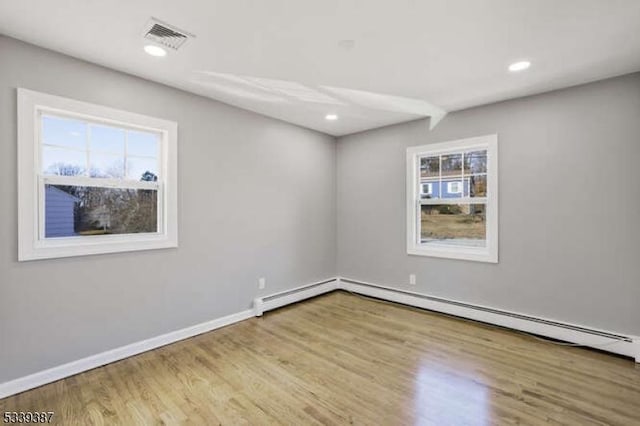 unfurnished room featuring a baseboard heating unit, baseboards, wood finished floors, and recessed lighting