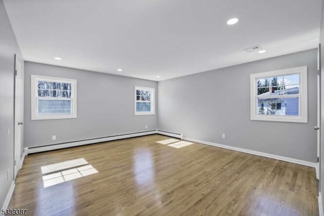 spare room featuring baseboards, baseboard heating, wood finished floors, and recessed lighting