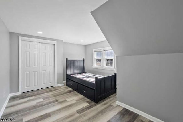 bedroom with a closet, wood finished floors, and baseboards