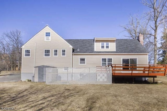 back of house with a deck, a yard, and a chimney