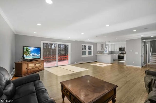 living room with stairway, baseboard heating, ornamental molding, light wood-style floors, and baseboards