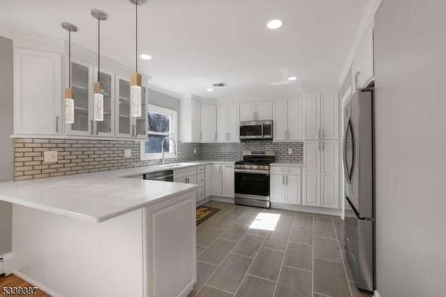 kitchen featuring decorative backsplash, appliances with stainless steel finishes, white cabinetry, a sink, and a peninsula