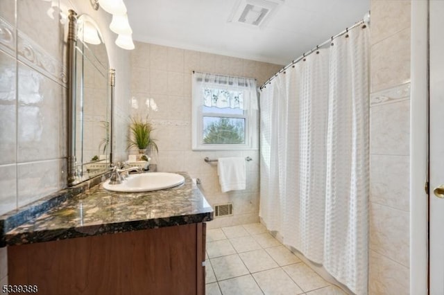 full bath featuring visible vents, vanity, tile patterned flooring, and tile walls