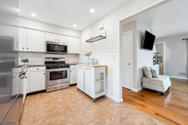 kitchen with tasteful backsplash, recessed lighting, appliances with stainless steel finishes, open floor plan, and white cabinets