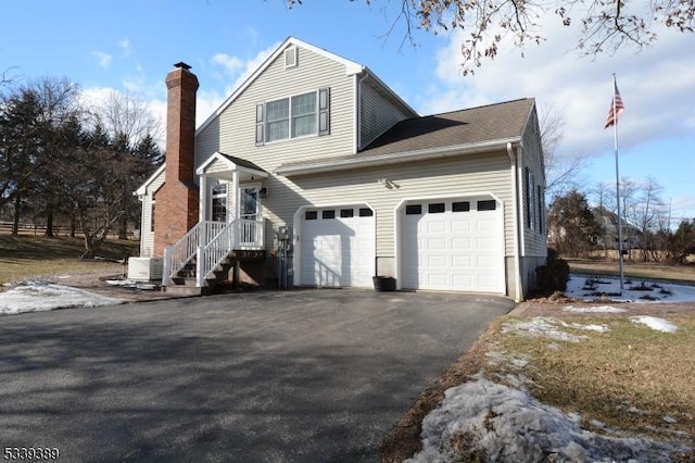 view of side of home with aphalt driveway, a chimney, and a garage