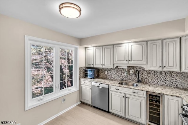 kitchen featuring beverage cooler, decorative backsplash, dishwasher, light stone counters, and a sink