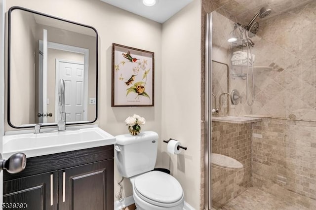 bathroom featuring toilet, a stall shower, baseboards, and vanity