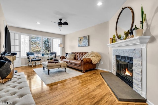 living area with a fireplace, light wood-style flooring, and baseboards