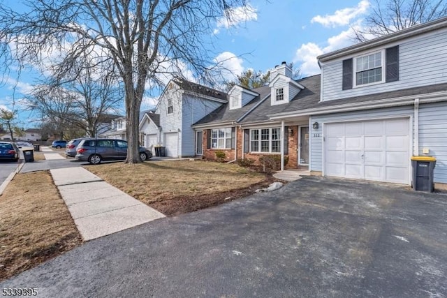 view of front of property featuring a garage, driveway, a chimney, a front lawn, and brick siding