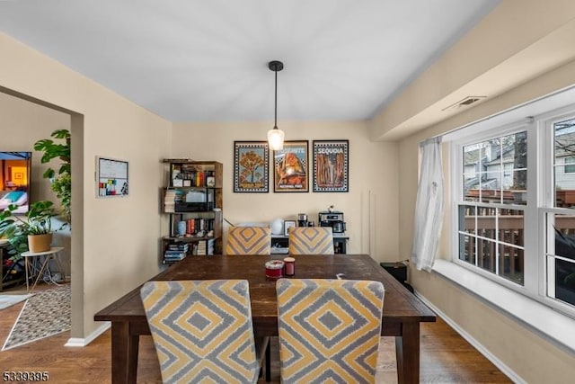 dining space featuring dark wood-type flooring, visible vents, and baseboards