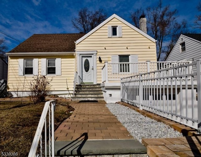 bungalow featuring a deck, a shingled roof, and a chimney