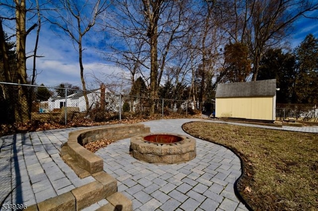 view of yard featuring a patio, a storage shed, a fenced backyard, an outdoor structure, and a fire pit