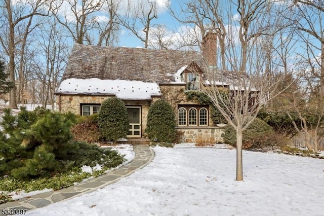 english style home featuring stone siding and a chimney