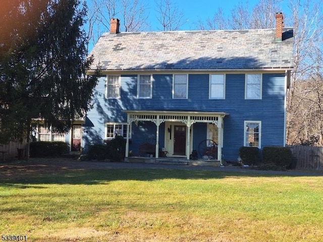 colonial home featuring a porch, a chimney, and a front yard